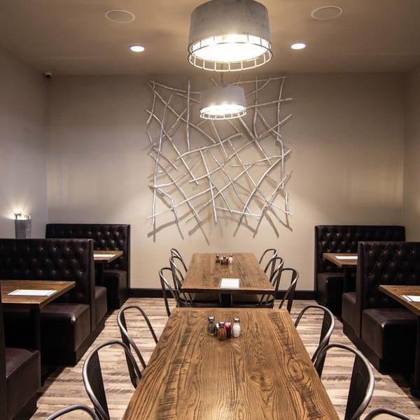 Picoso's Mexican Kitchen dining room with wooden tables, black booths, and a modern wall art piece.