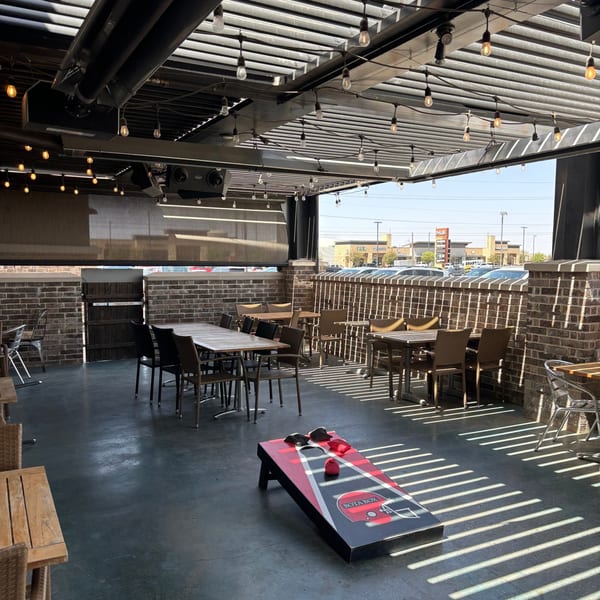 Picoso's Mexican Kitchen outdoor patio with tables, string lights, and a cornhole game under a pergola.
