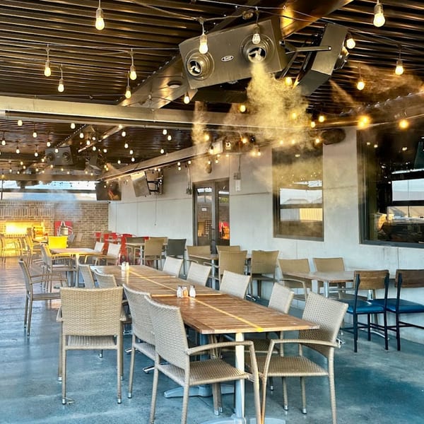 Picoso's Mexican Kitchen outdoor patio with string lights, misters, and empty tables and chairs.