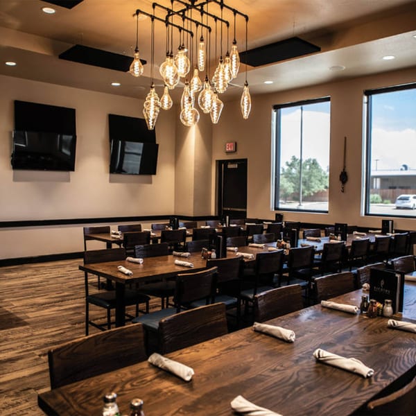 Picoso's Mexican Kitchen dining room with dark wooden tables, chairs, and industrial light fixtures.