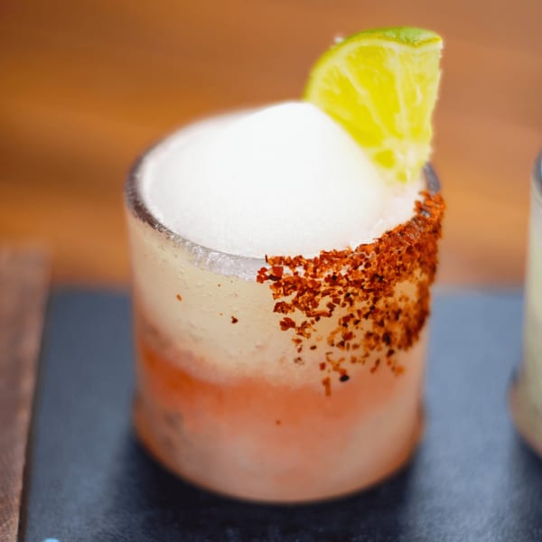 A Picoso's Mexican Kitchen frozen margarita with a chili-lime rim and a lime wedge.