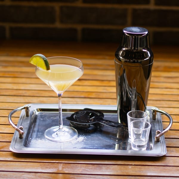 Picoso's Mexican Kitchen margarita with lime, cocktail shaker, and shot glasses on a silver tray.