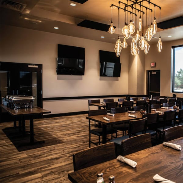 Picoso's Mexican Kitchen dining room with wooden tables, chairs, and a buffet station under industrial lighting.
