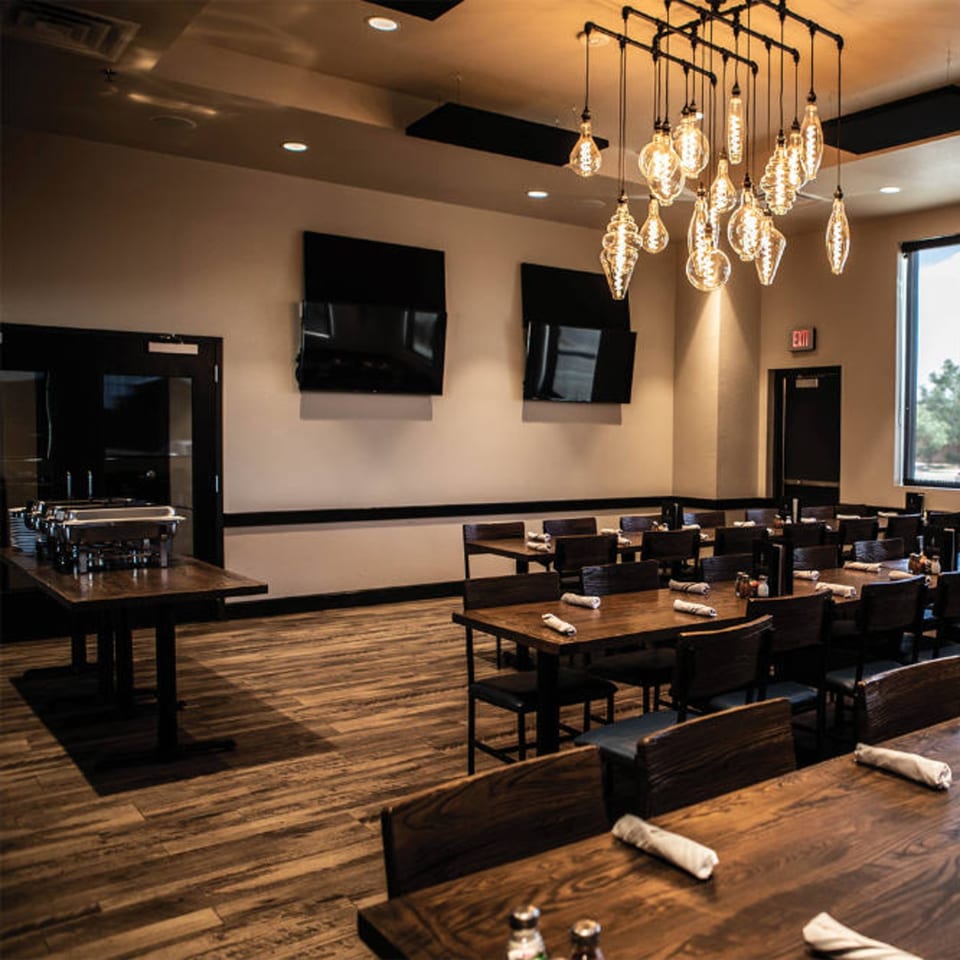 Picoso's Mexican Kitchen dining room with wooden tables, chairs, and a buffet station under industrial lighting.