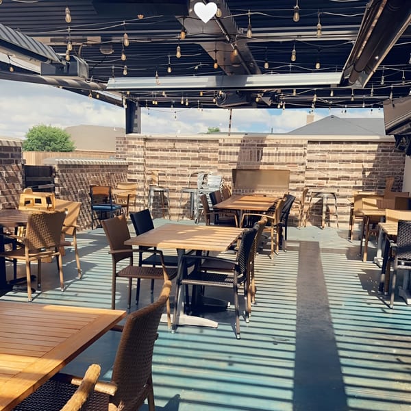 Picoso's Mexican Kitchen's outdoor patio with empty tables and chairs under string lights.